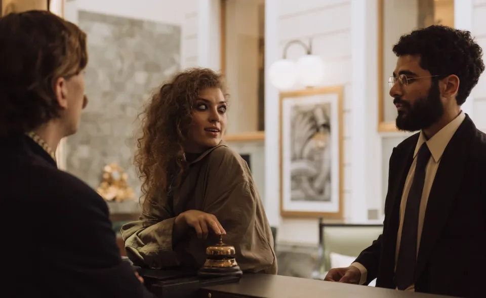 A guest at a hotel front desk talks with the receptionist